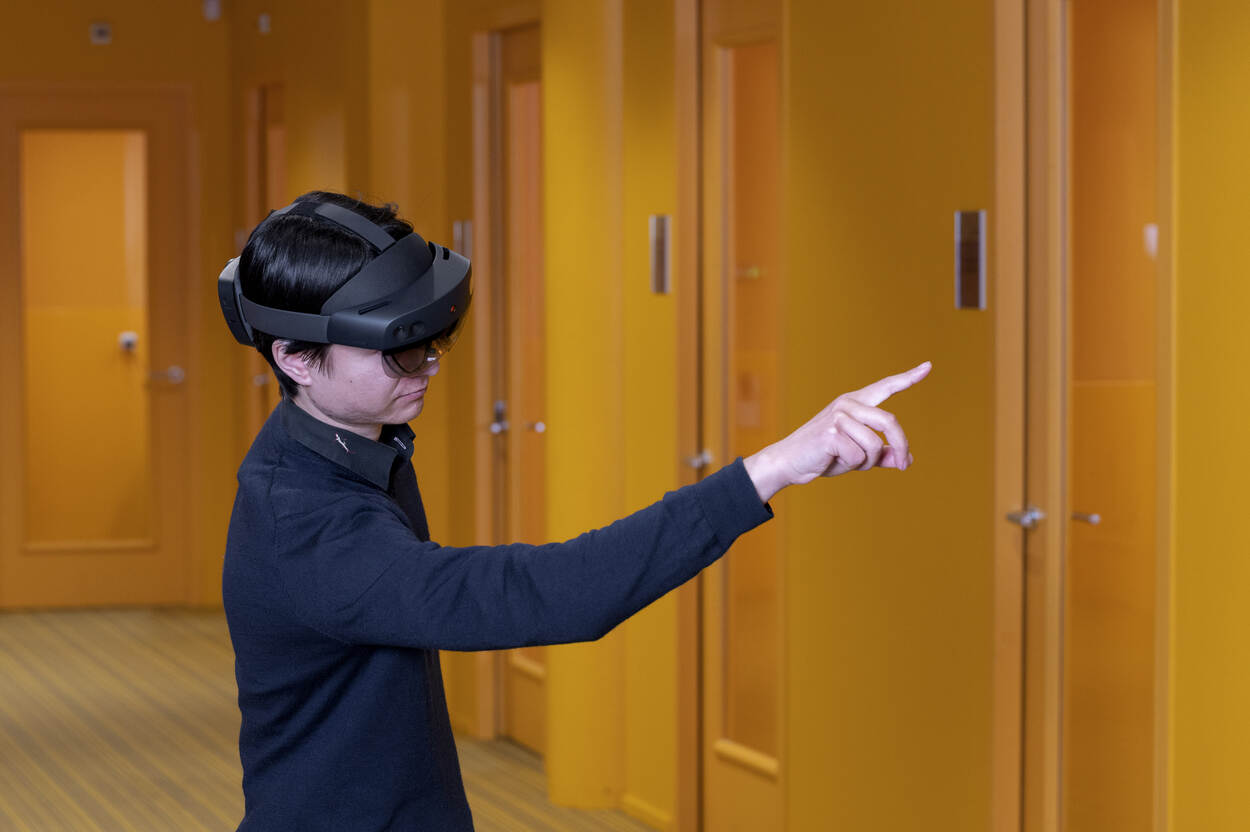 Jong persoon met VR-bril op wijst in de lucht