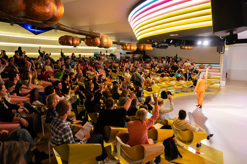 zaal met mensen en dagvoorzitter